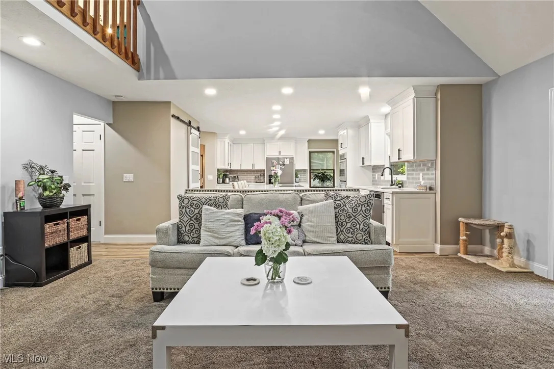 Living room featuring a barn door, recessed lighting, and light carpet