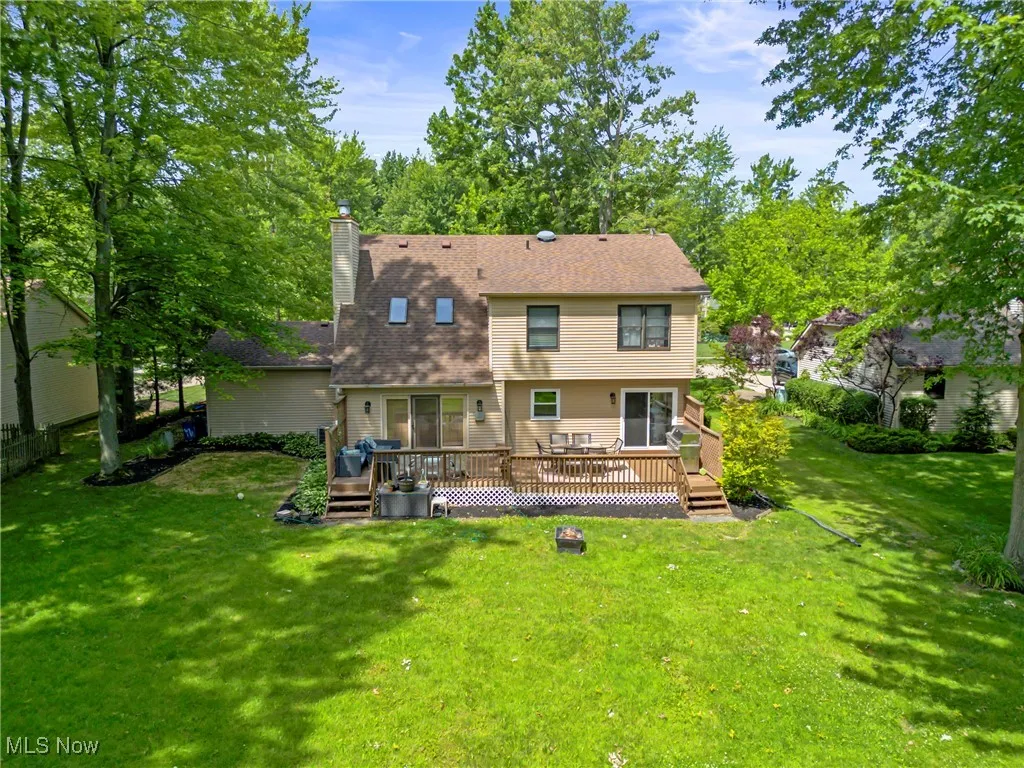 Back of property featuring a lawn, a wooden deck, a chimney, and roof with shingles