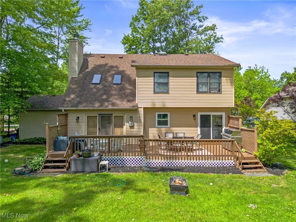 Back of property with a fire pit, a deck, a chimney, and a yard