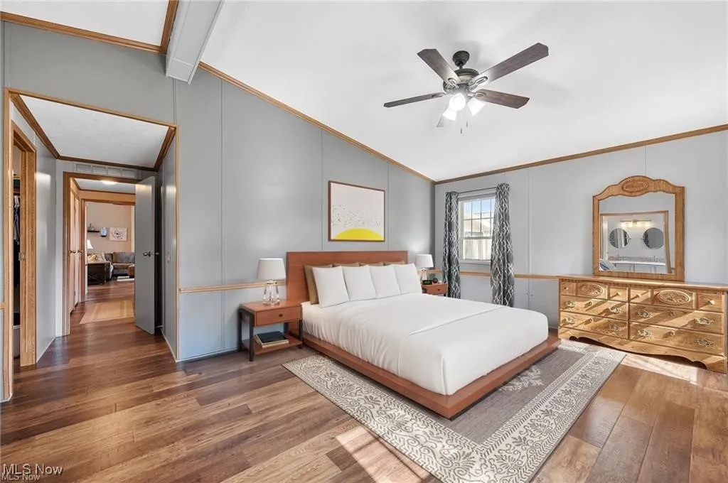 Bedroom with vaulted ceiling, crown molding, wood finished floors, and ceiling fan