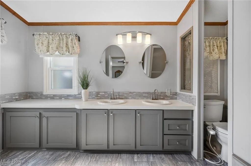 Full bathroom with double vanity and ornamental molding