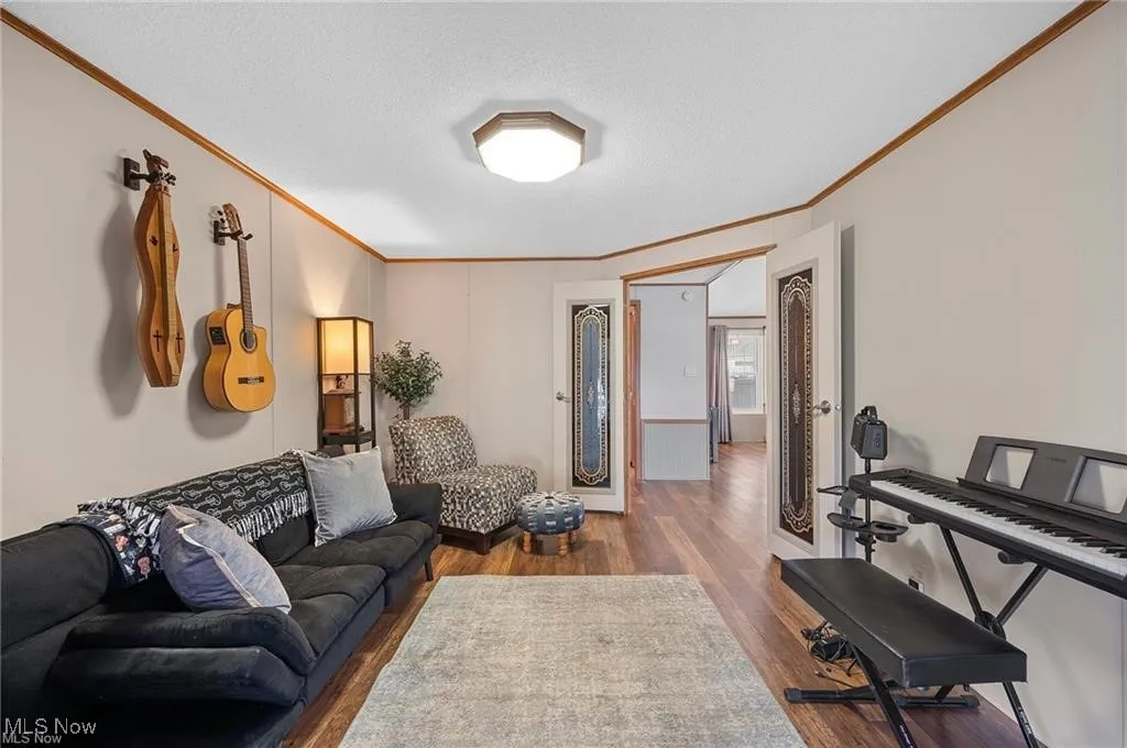 Den with crown molding, wood finished floors, and a textured ceiling