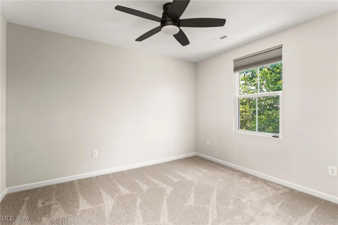 Carpeted spare room featuring baseboards and ceiling fan