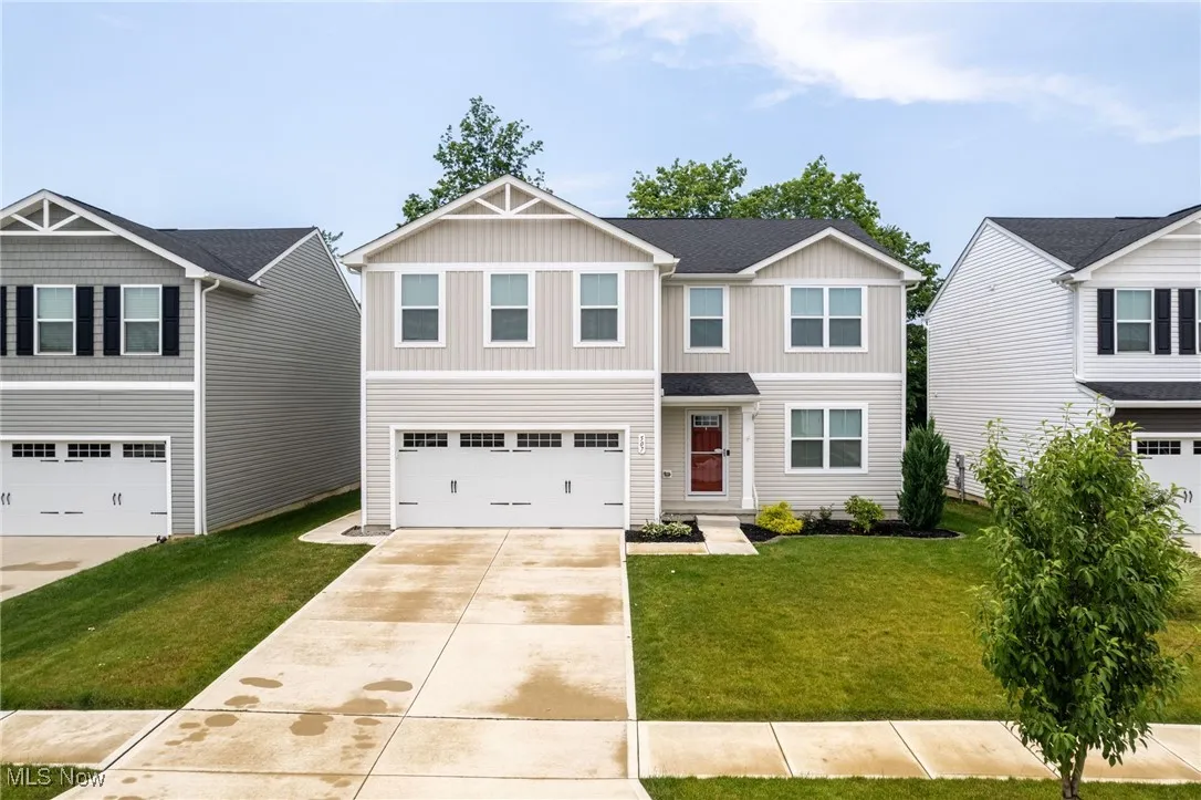 View of front of house with board and batten siding, concrete driveway, a garage, and a front lawn