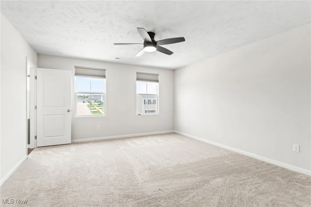 Unfurnished room with ceiling fan, carpet floors, and a textured ceiling