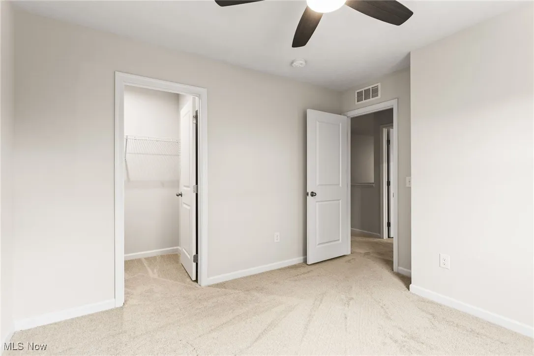 Unfurnished bedroom featuring carpet, a walk in closet, ceiling fan, and a closet