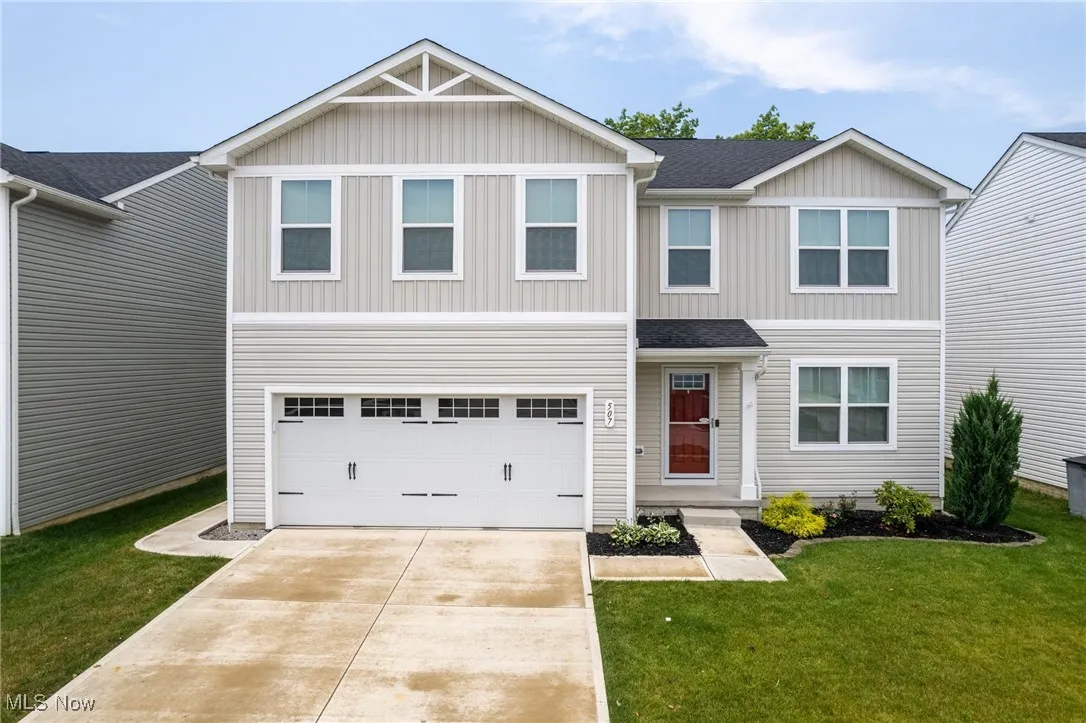 Traditional-style home with board and batten siding, driveway, a garage, and a front lawn
