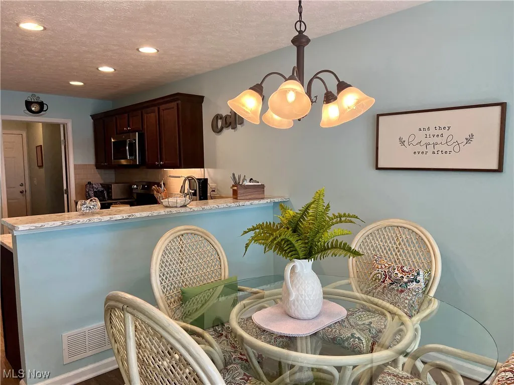 Kitchen with stainless steel microwave, range with electric stovetop, a chandelier, recessed lighting