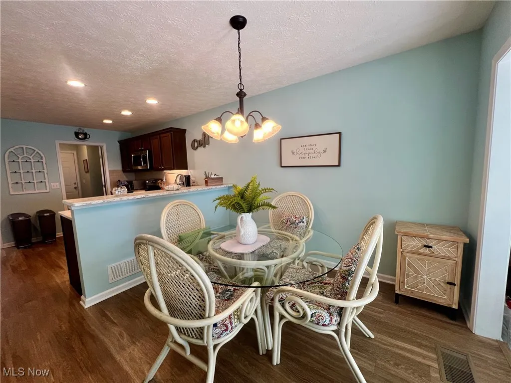 Dining room with dark wood-style floors, a chandelier, recessed lighting