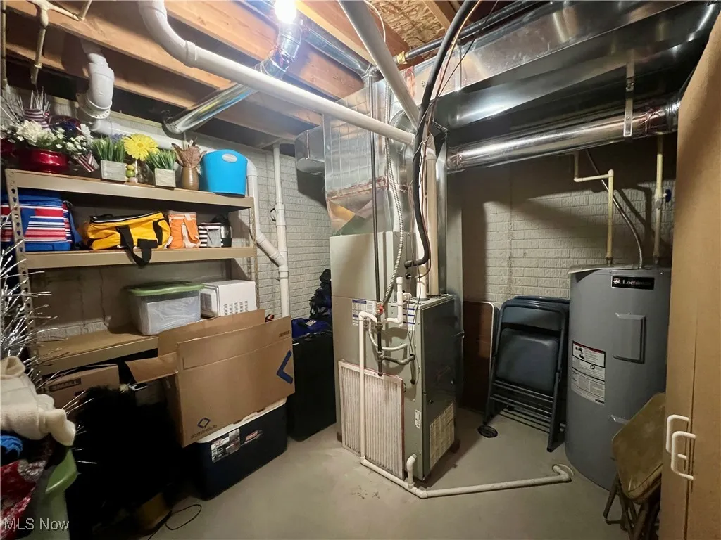 Utility room featuring electric water heater and heating unit