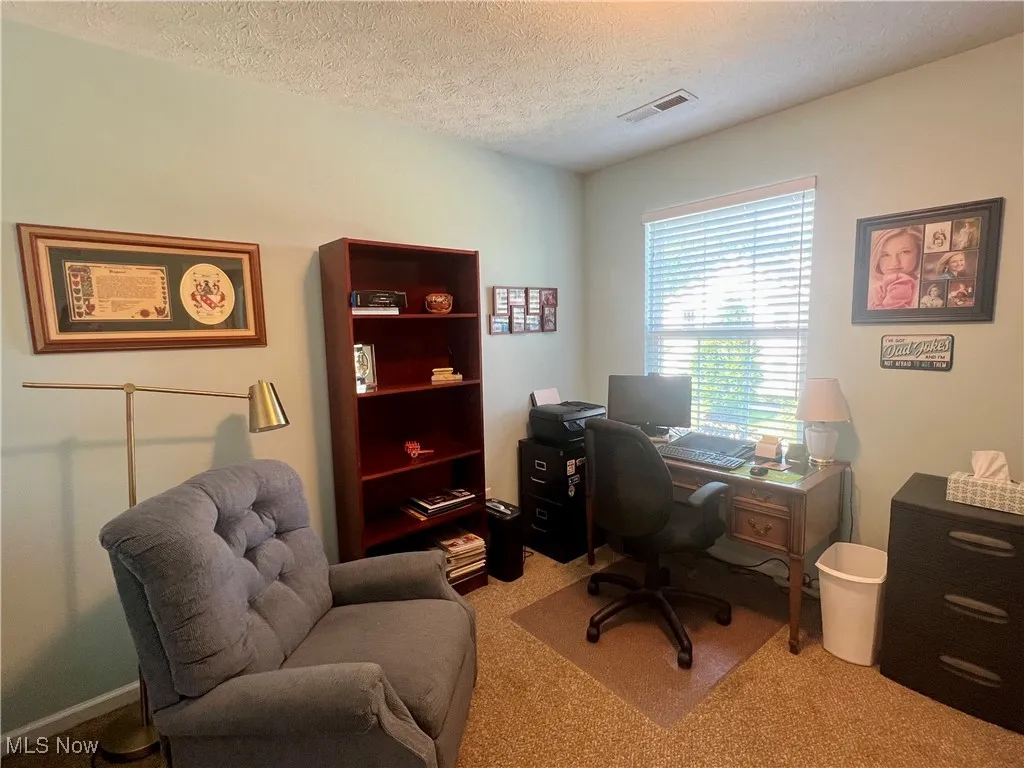 Carpeted office space featuring a textured ceiling