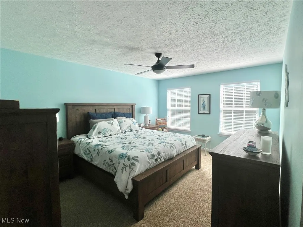 Bedroom featuring light colored carpet, ceiling fan, and a textured ceiling