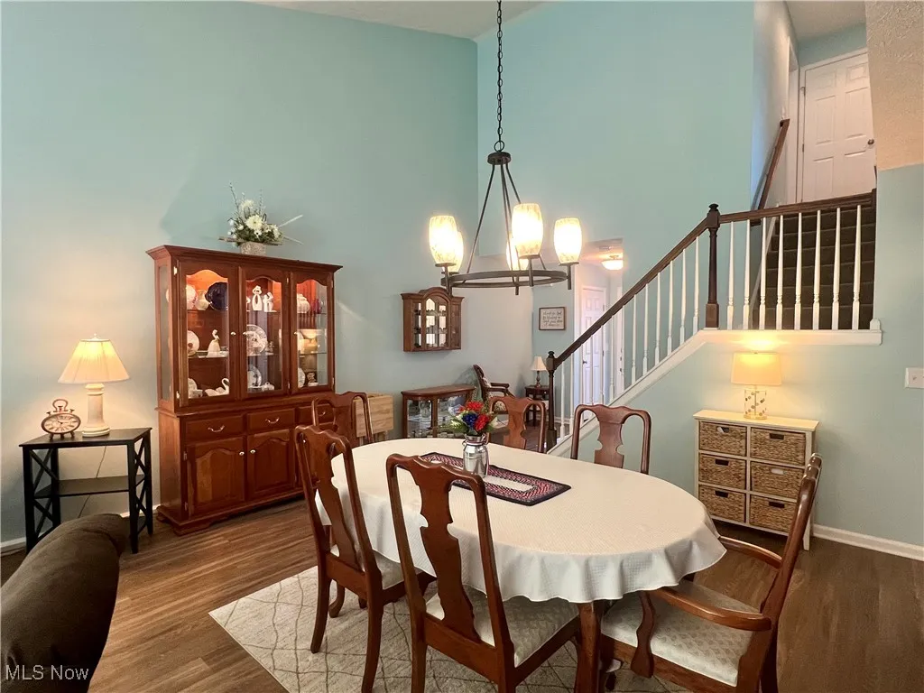 Dining room featuring a chandelier, wood finished floors, high vaulted ceiling, and stairway