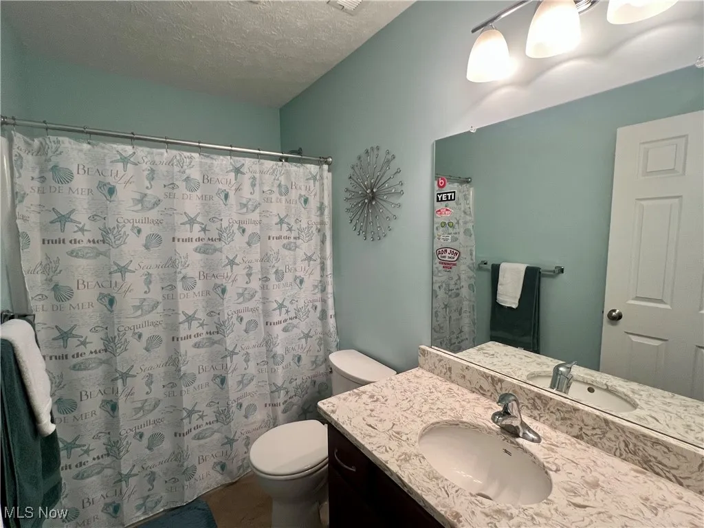 Full bath featuring a textured ceiling, vanity, curtained shower, and tile patterned flooring