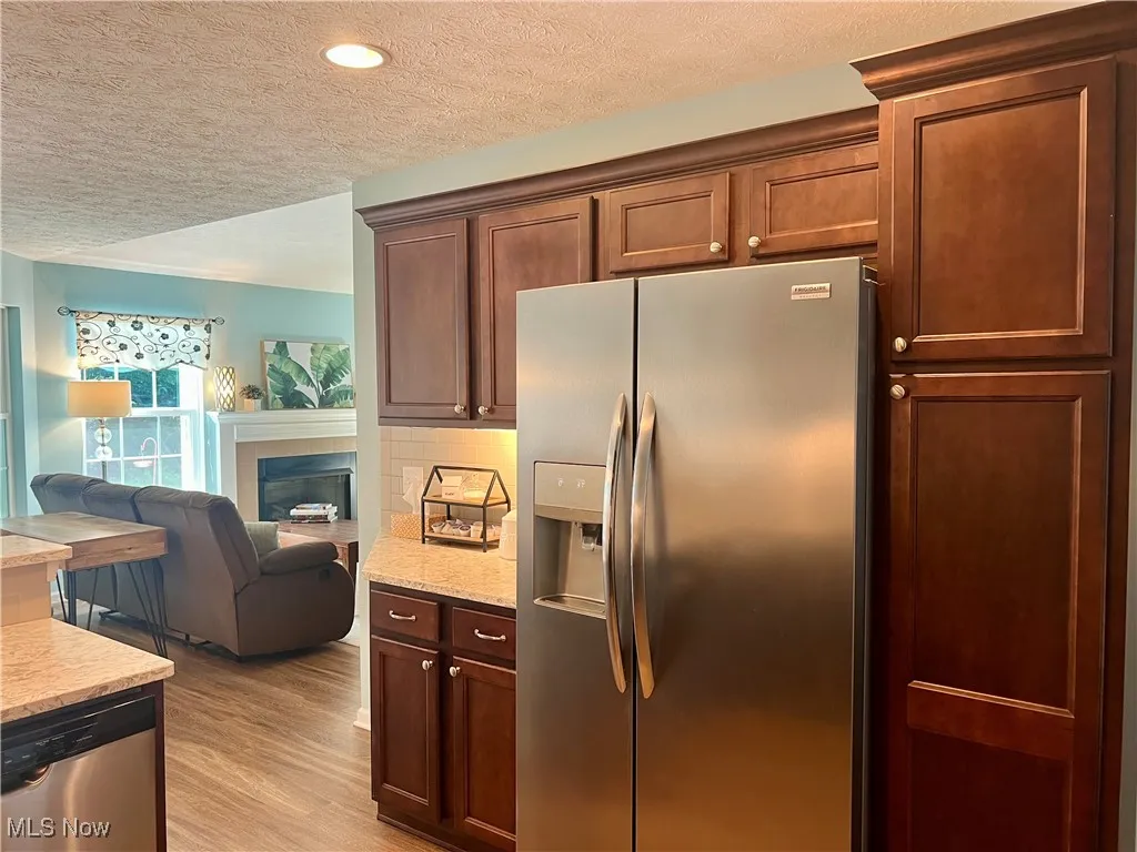 Kitchen featuring appliances with stainless steel finishes, a textured ceiling, open floor plan, light wood-type flooring