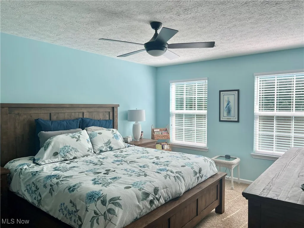 Bedroom with light colored carpet, a textured ceiling, and a ceiling fan