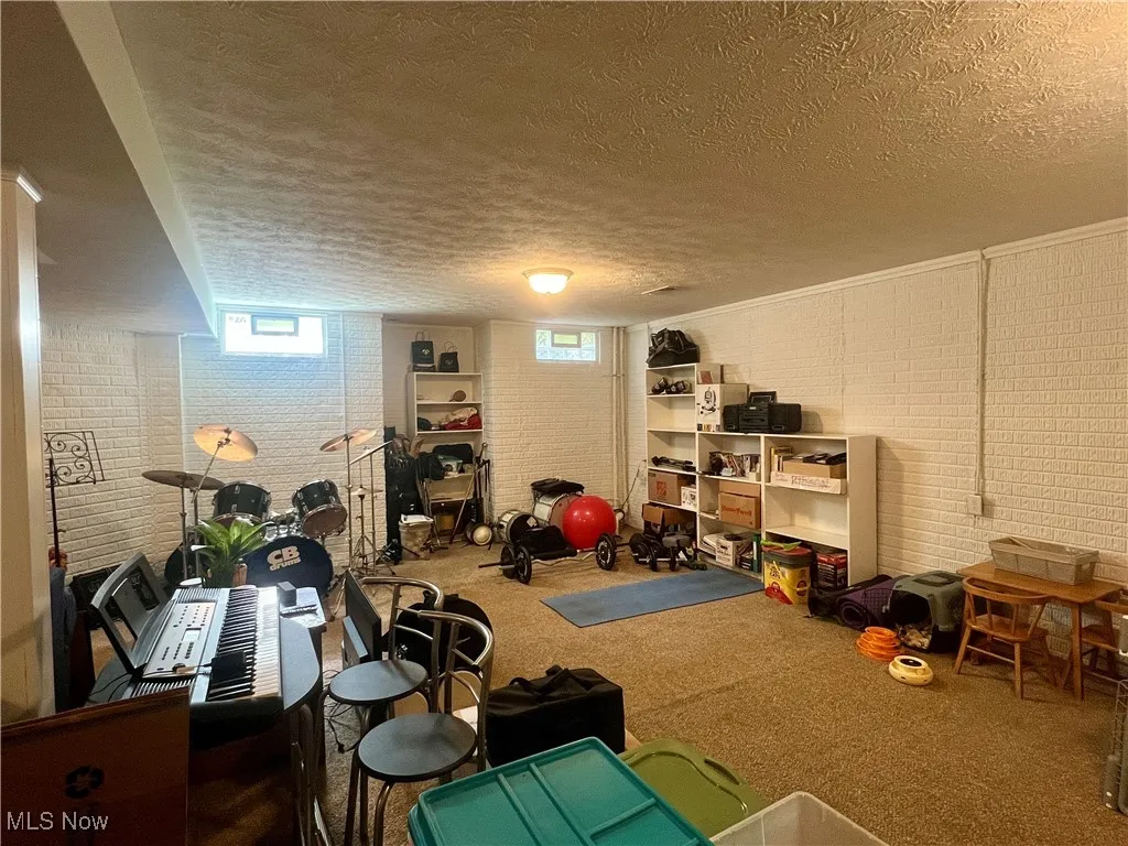 Exercise area featuring a textured ceiling, brick wall, and carpet flooring