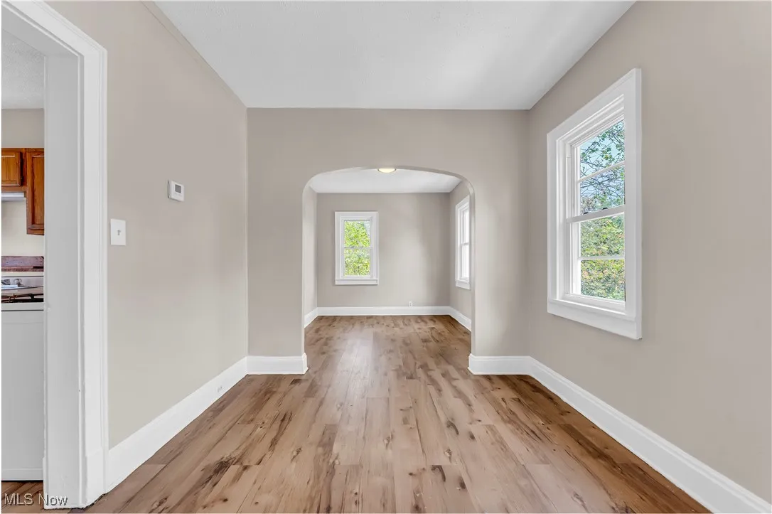 Spare room featuring arched walkways and light wood-style floors