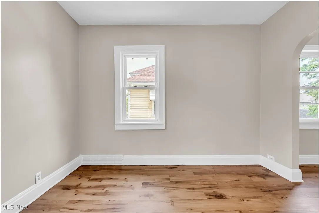 Empty room featuring arched walkways and wood finished floors