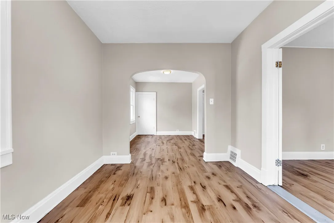 Spare room featuring arched walkways and light wood finished floors
