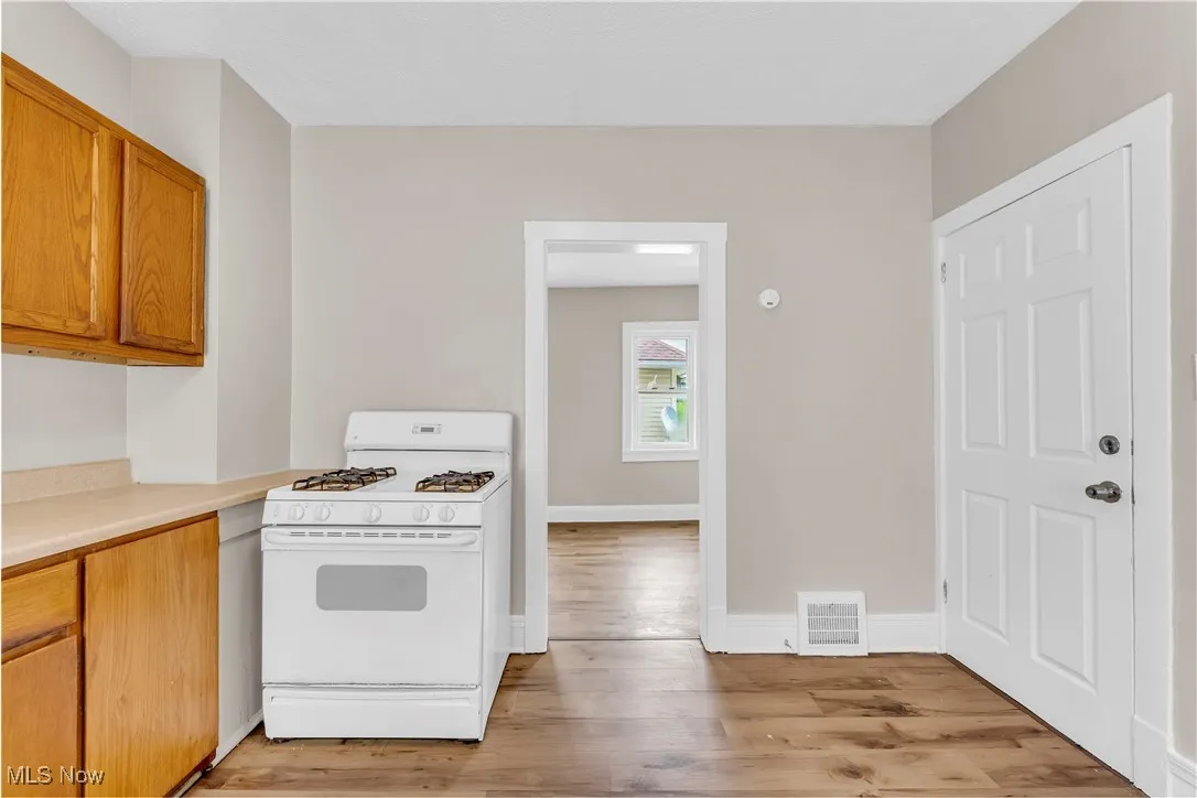 Kitchen with gas range gas stove, light wood-style floors, light countertops, and brown cabinetry