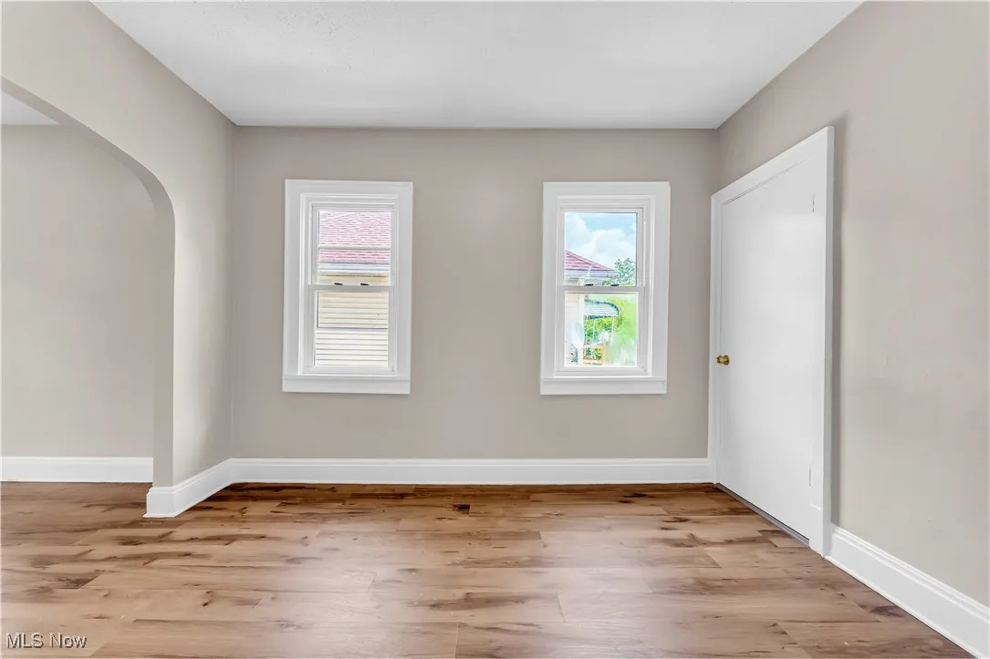 Unfurnished room with light wood-style floors, healthy amount of natural light, and arched walkways