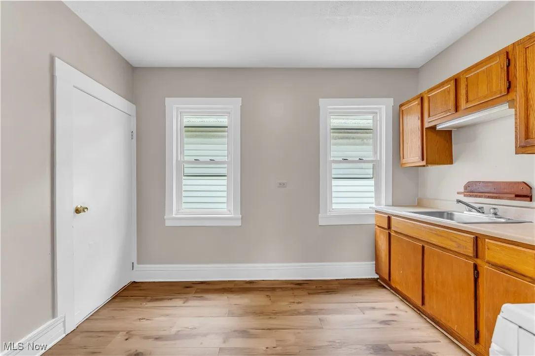 Kitchen featuring white gas stove, light countertops, light wood-type flooring, and brown cabinets