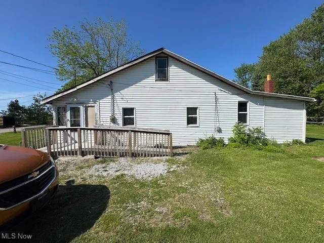 View of home's exterior with a lawn, a deck, and a chimney