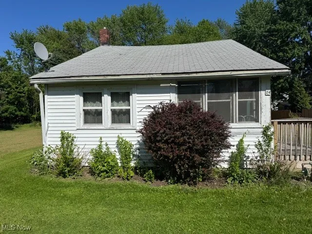 View of side of property with a yard, a chimney, and roof with shingles