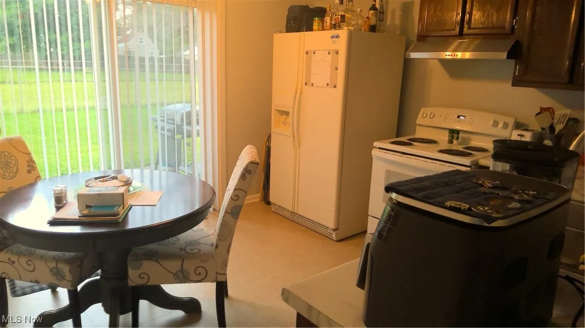 Kitchen featuring fridge, range, ventilation hood, and healthy amount of natural light