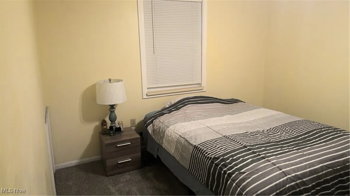 Bedroom featuring dark carpet and baseboards