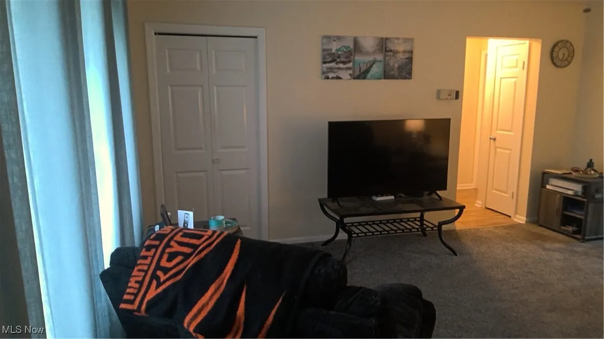 Carpeted living area featuring baseboards