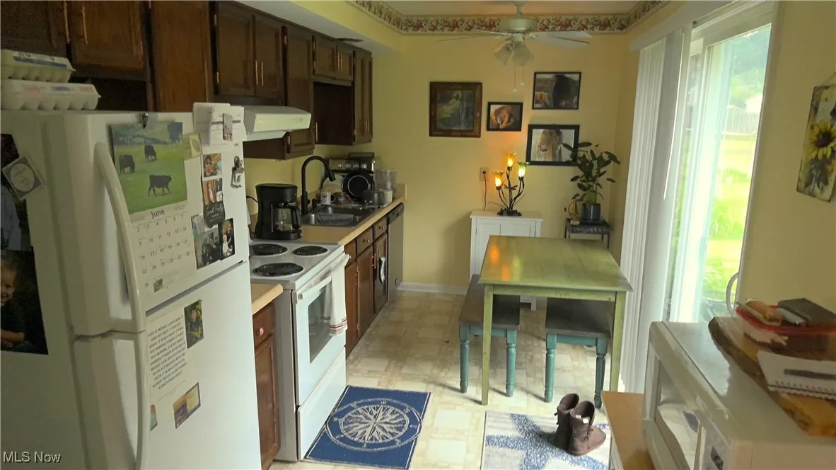 Kitchen with white appliances, plenty of natural light, light floors, and ceiling fan