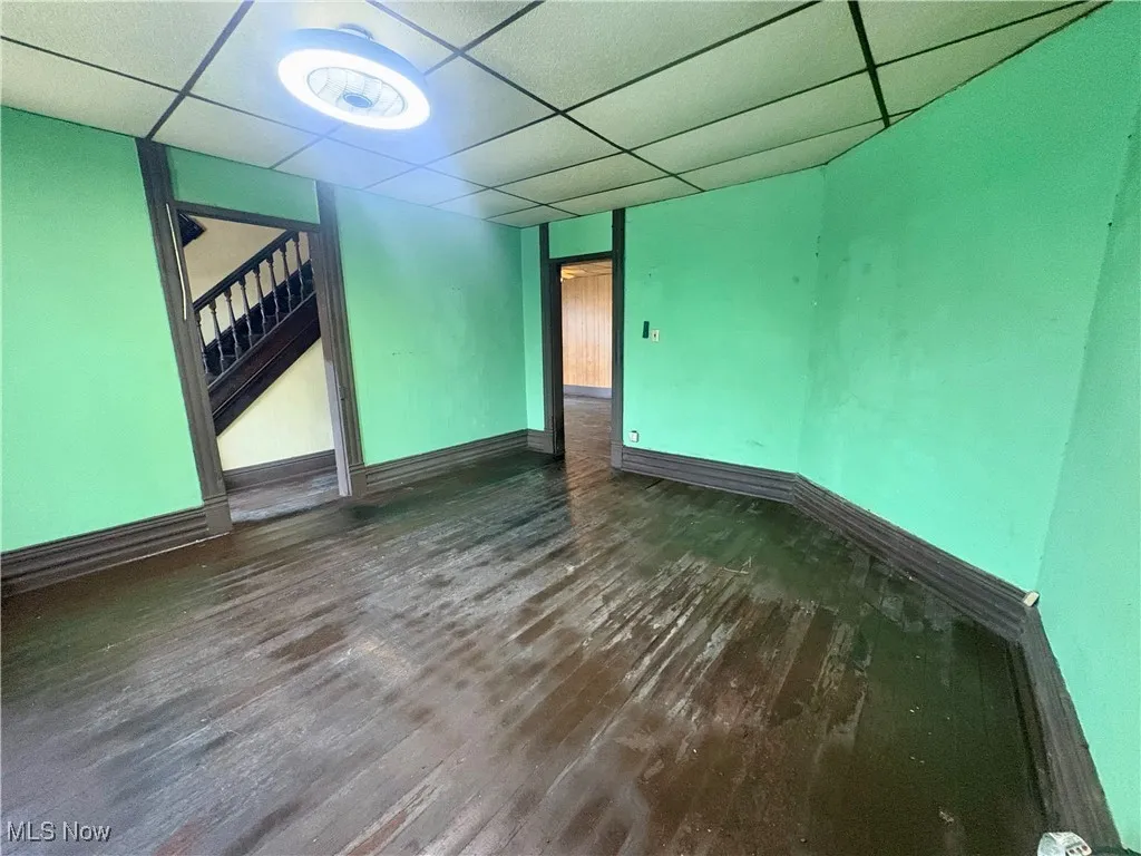 Unfurnished room featuring a paneled ceiling, wood finished floors, and stairs
