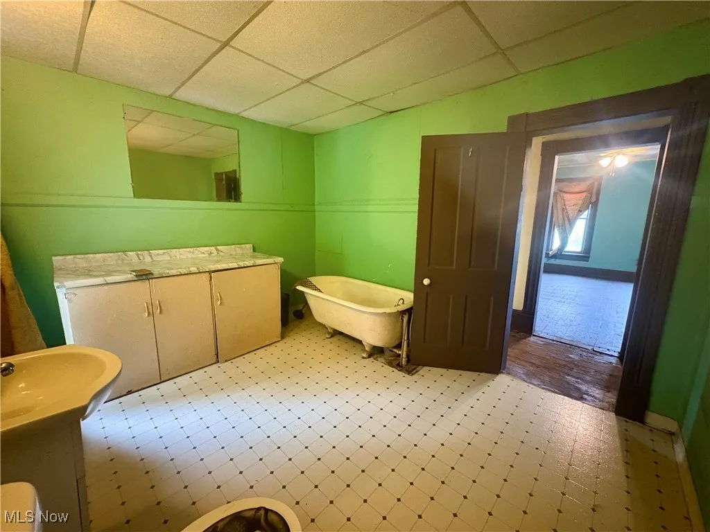 Bathroom featuring a drop ceiling, a soaking tub, vanity, and tile patterned floors