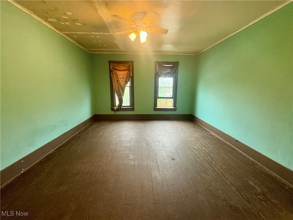 Spare room featuring a ceiling fan, wood-type flooring, and ornamental molding