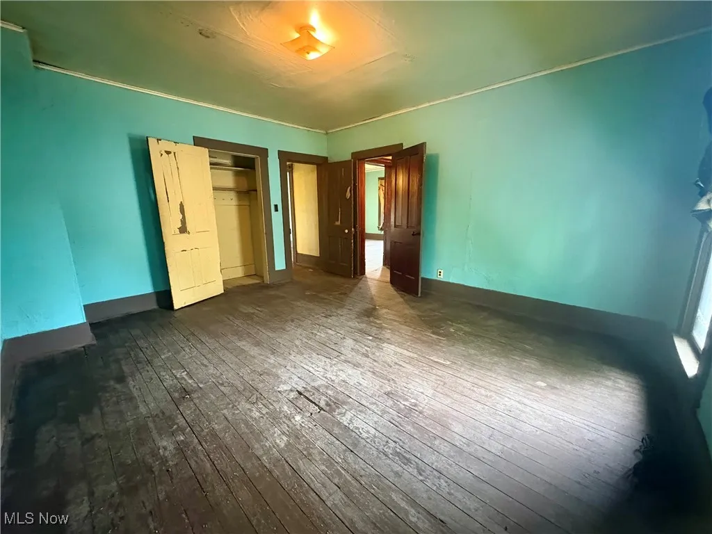 Unfurnished bedroom featuring hardwood / wood-style floors and baseboards