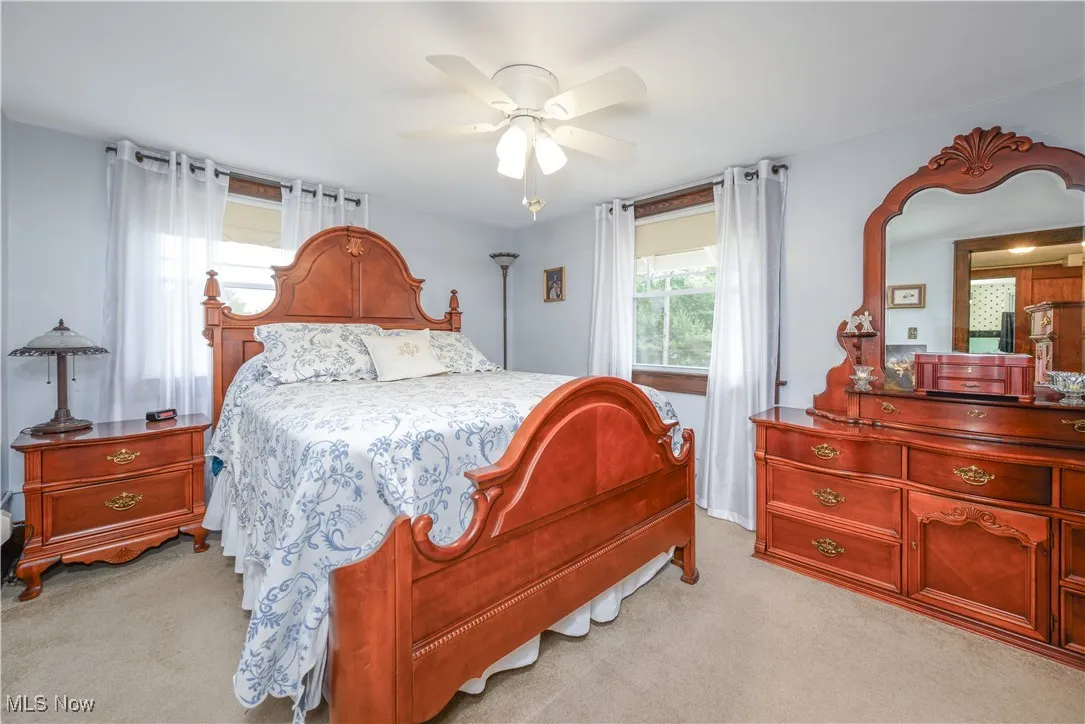 Bedroom #1 with light carpet/ wood flooring beneath and ceiling fan.