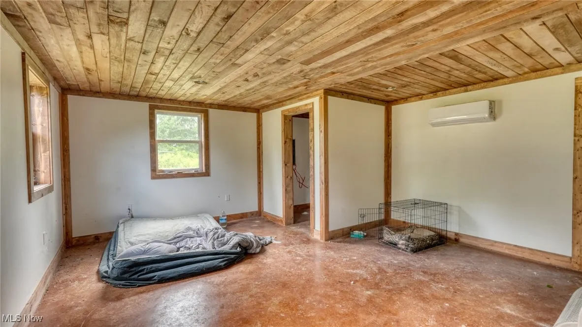 Unfurnished bedroom with wooden ceiling and a wall mounted AC