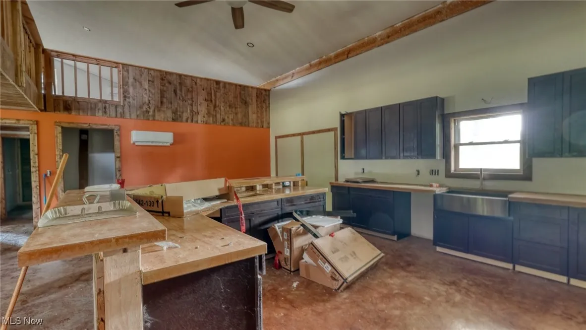 Kitchen with a towering ceiling, a ceiling fan, blue cabinets, concrete flooring, and light countertops