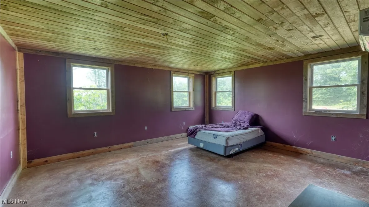 Unfurnished room with wood ceiling, plenty of natural light, and concrete floors