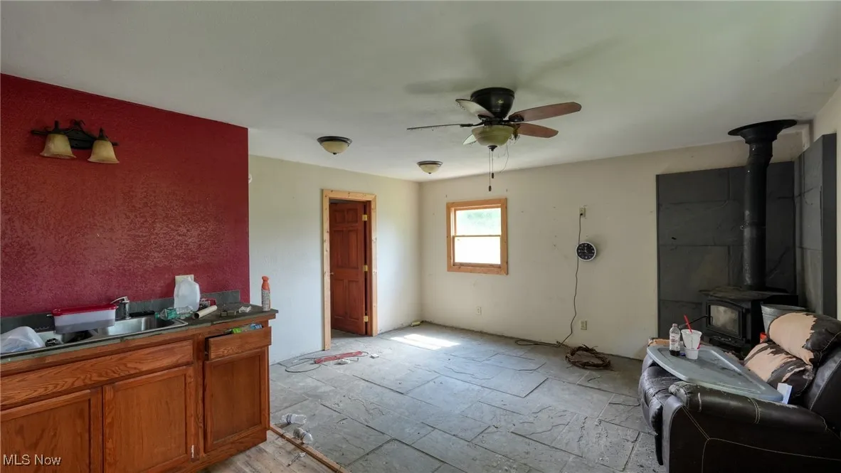 Living room featuring a wood stove and ceiling fan