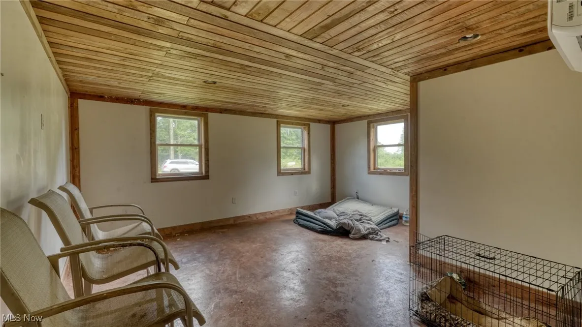 Unfurnished room featuring concrete floors, wooden ceiling, and a wall unit AC
