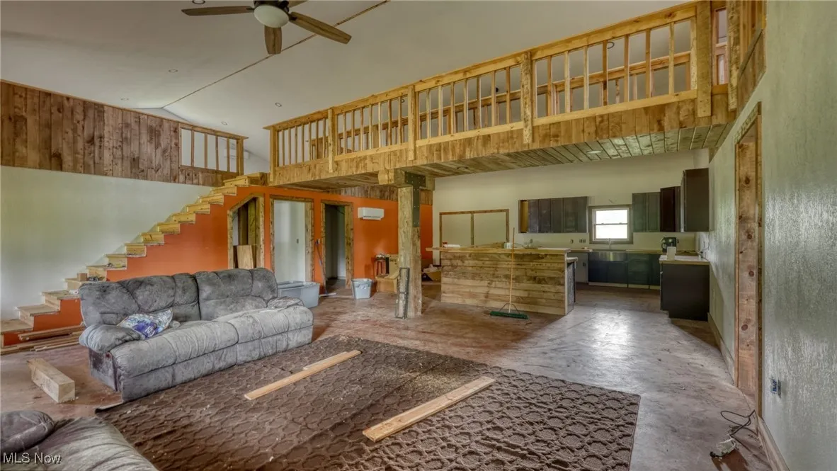 Living area featuring ceiling fan, stairway, and high vaulted ceiling