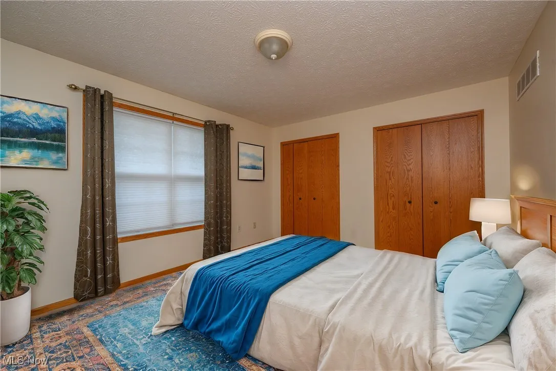 Bedroom with multiple closets and a textured ceiling