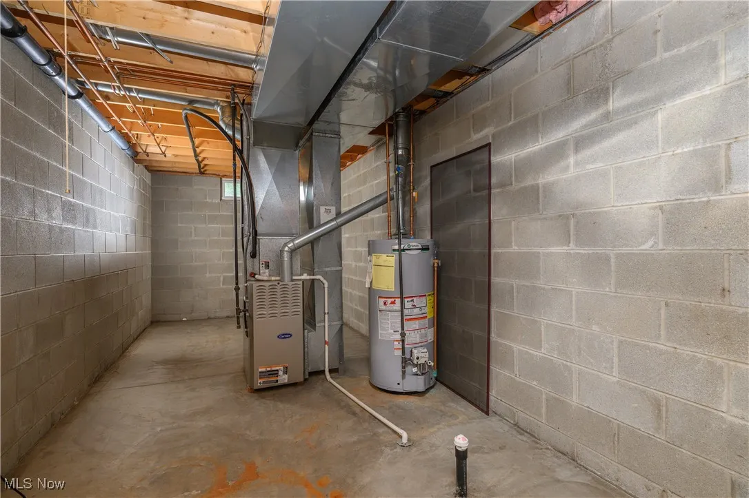 Utility room featuring water heater and heating unit
