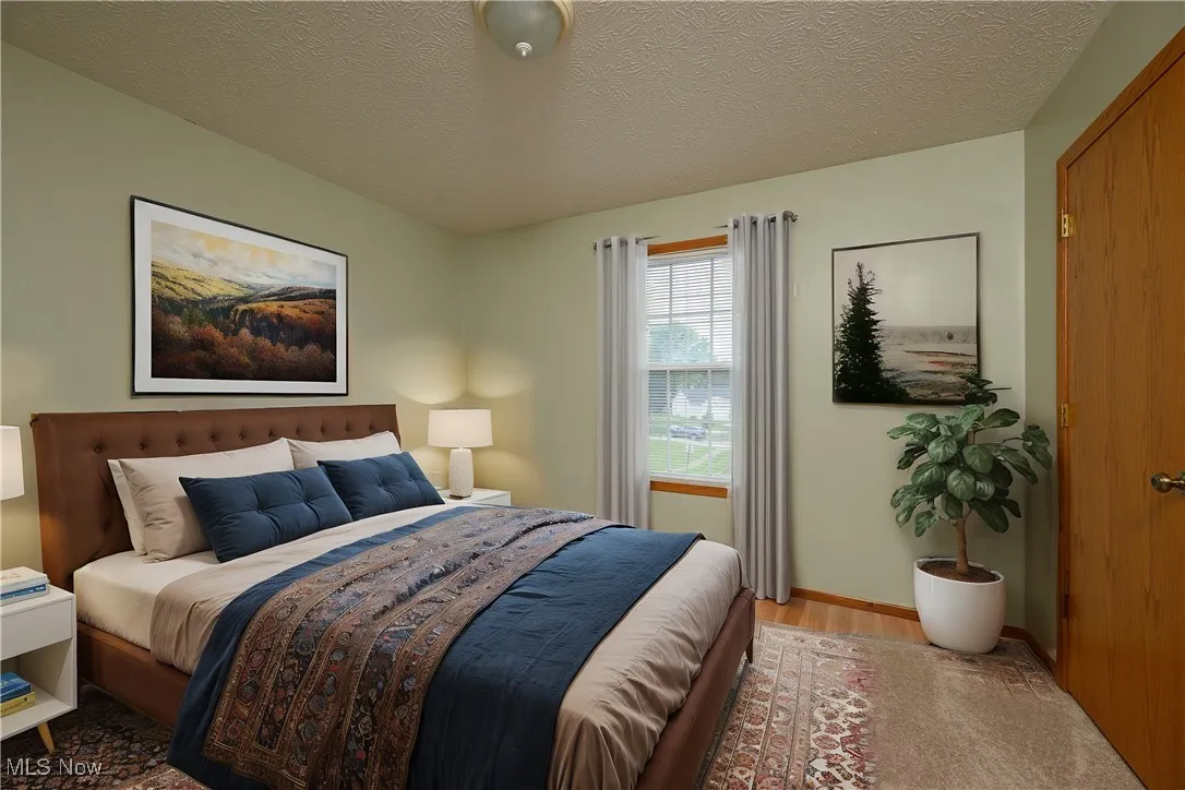 Bedroom with a textured ceiling and light hardwood / wood-style flooring