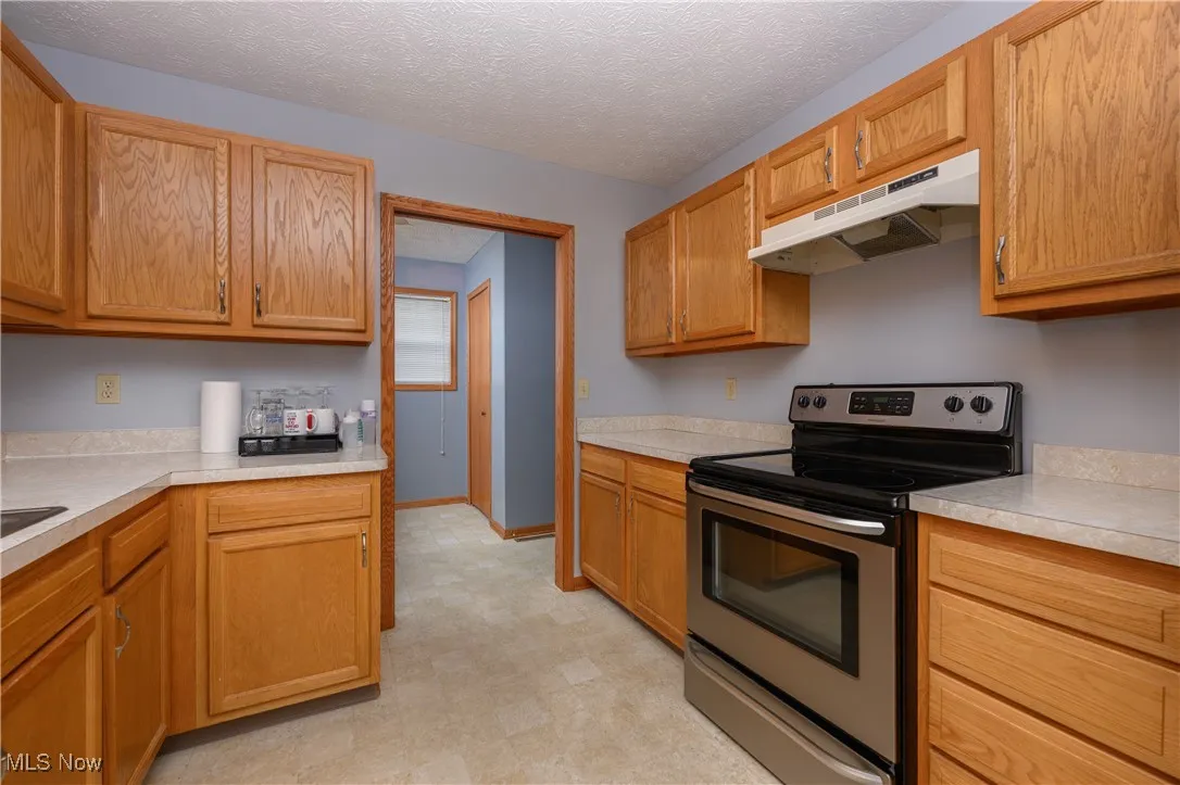 Kitchen featuring a textured ceiling and stainless steel electric stove