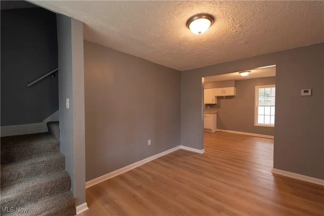 Unfurnished living room featuring light wood-style LVP floors, a textured ceiling, and stairway