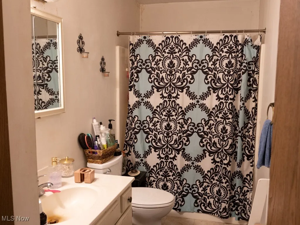 Full bath with vanity, curtained shower, and tile patterned floors